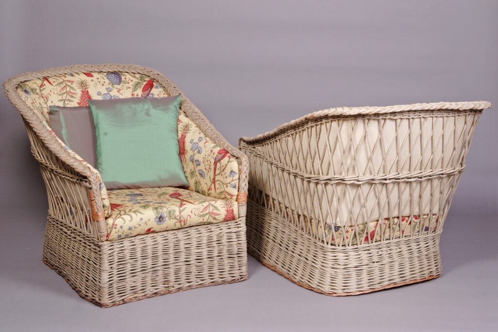 Para foteli-berżer z wikliny, lakierowanych na kremowo, wyściełanych wzorzystą tkaniną.