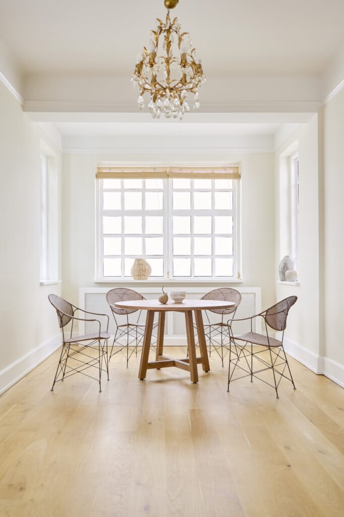 Cztery krzesła Funky z rattanu i metaloej ramy w jasnym pokoju przy drewnianym, okrągłym stole, podłoga drewniana, ściany białe.