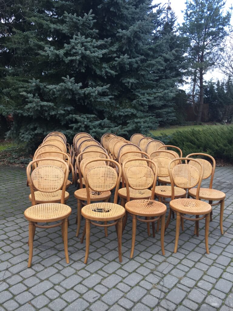 Grupa kilkunastu krzeseł giętych z uszkodzoną plecionką oczekujących na naprawę