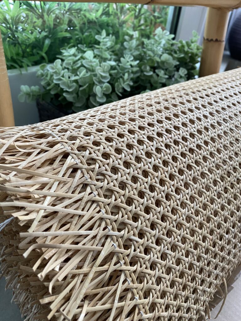 Widok na plecionkę rattanową w rolce w tle zielone rośliny