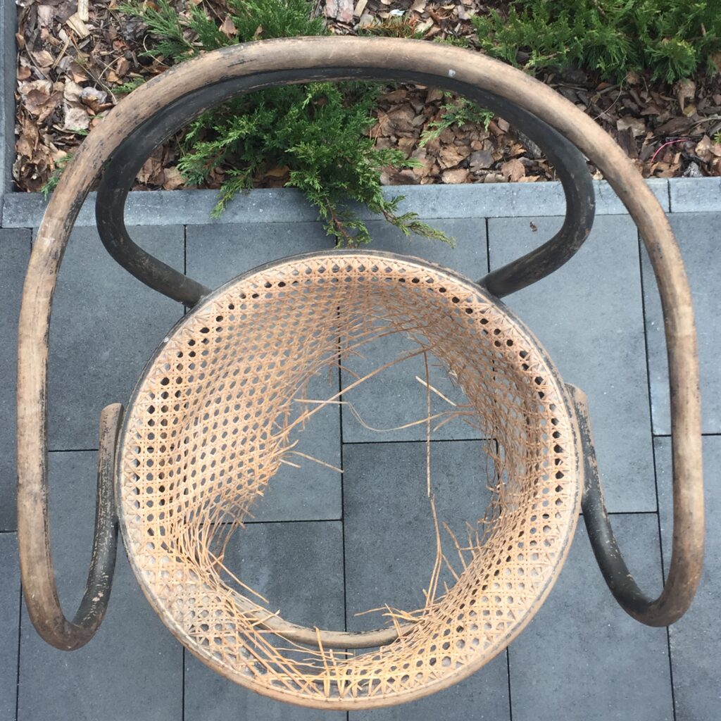Uszkodzony mebel Thonet. Widok z góry, widać rozerwaną plecionkę rattanową w siedzisku