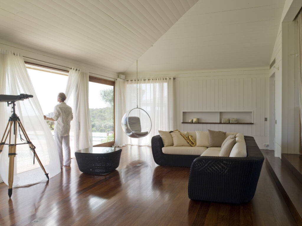 Sofy ogrodowe w formie narożnika stoją we wnętrzu przy tarasie. kolor sof czarny, poduszki białe.