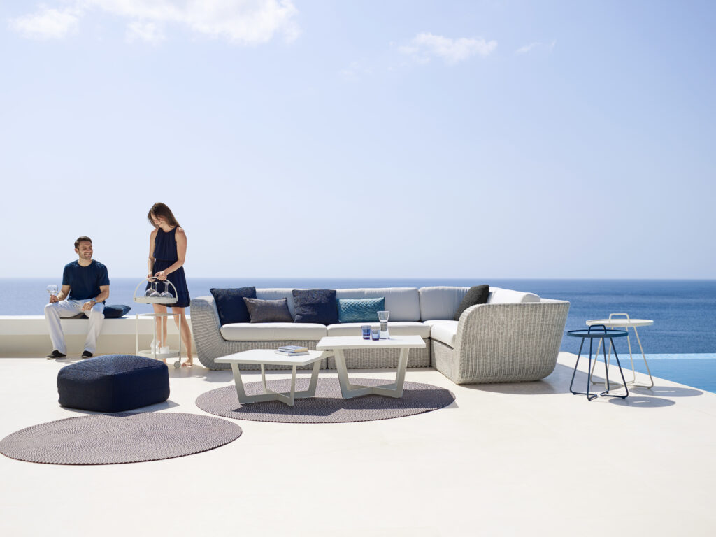 Przestronny taras, salon bez ścian z dużym zestawem białych mebli ogrodowych, duże sofy w formie naroąnika