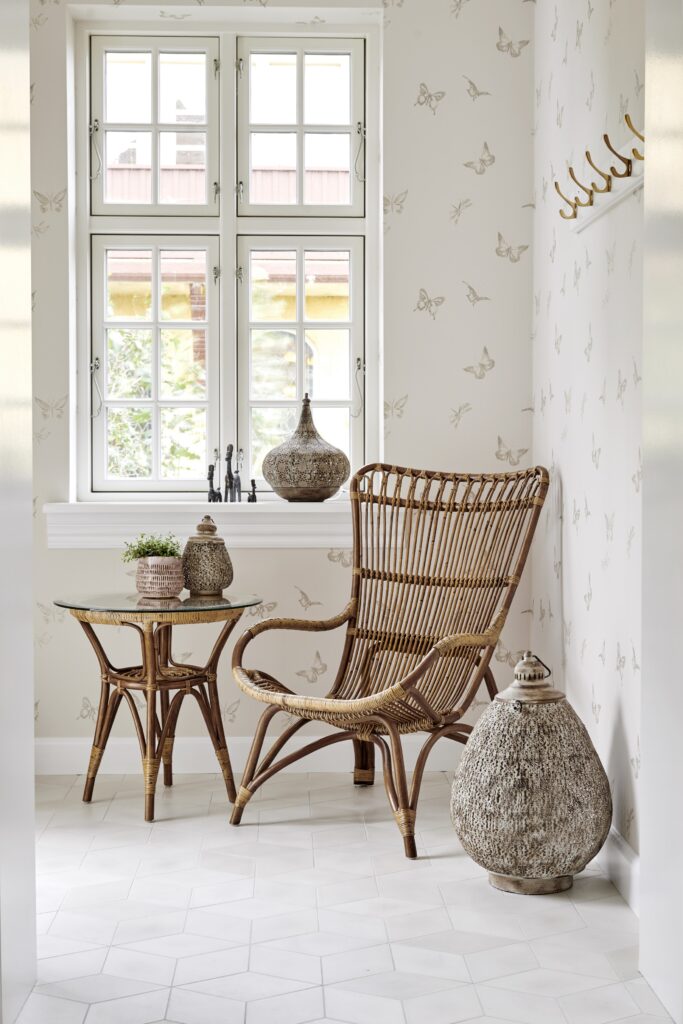 w kącie pokoju stoi wygodny fotel rattanowy Monet, kolor naturalny, obok mały, okrągły stolik kawowy z szybą