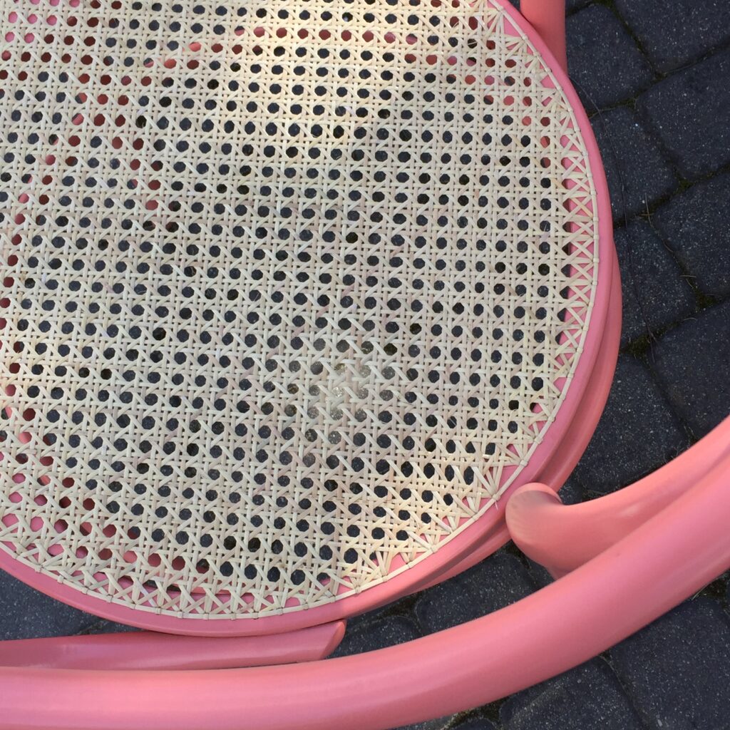 Widok od góry różowego krzesła giętego z jasną plecionką rattanową