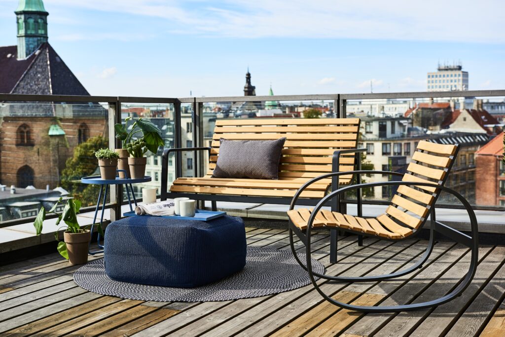 Piękny taras na dachu w centrum miasta z meblami teakowymi na metalowych ramach