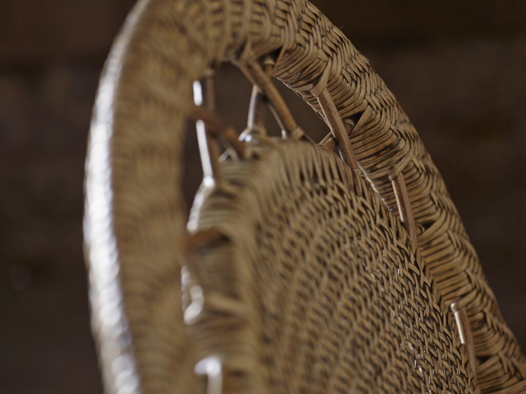 Widok na oparcie krzesła z rattanu, widoczne misterne sploty i solidna konstrukcja, kolor miodowy