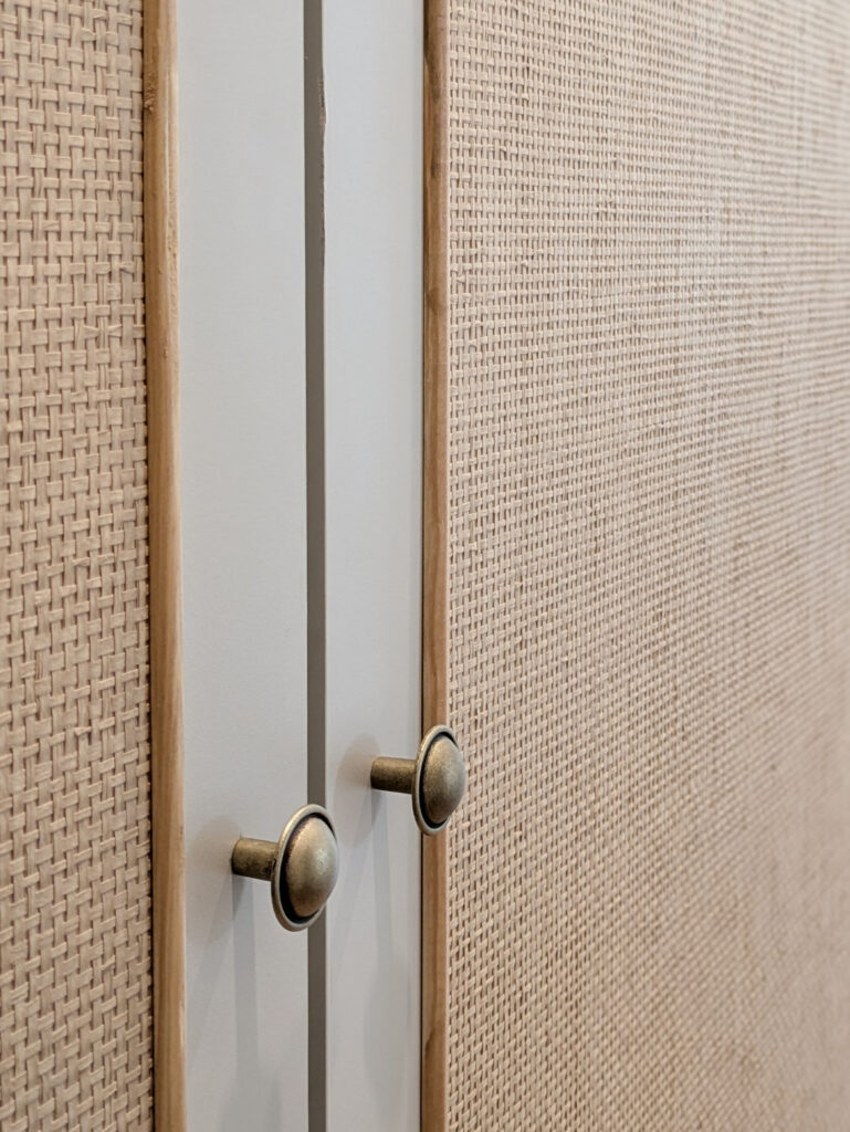 zbliżenie na drzwi szafy oklejonej tapetą z plecionki papierowej w kolorze beżowym