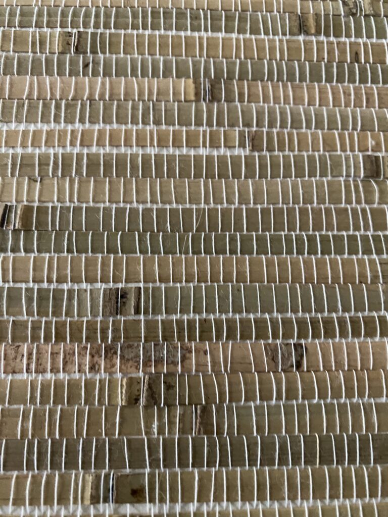 zbliżenie na tapetę z pasków bambusa, widoczne przerosty i różne odcienie bambusa oraz nitki montażowe, kolory -odcienie beżu i zieleni