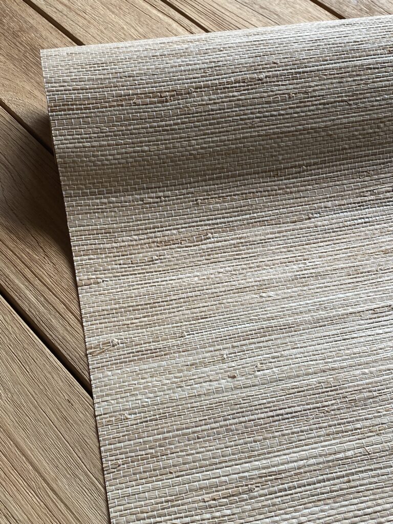 zbliżenie na rolkę tapety z łyka bananowca, kolor jasno szary, rolka leży na stole drewnianym