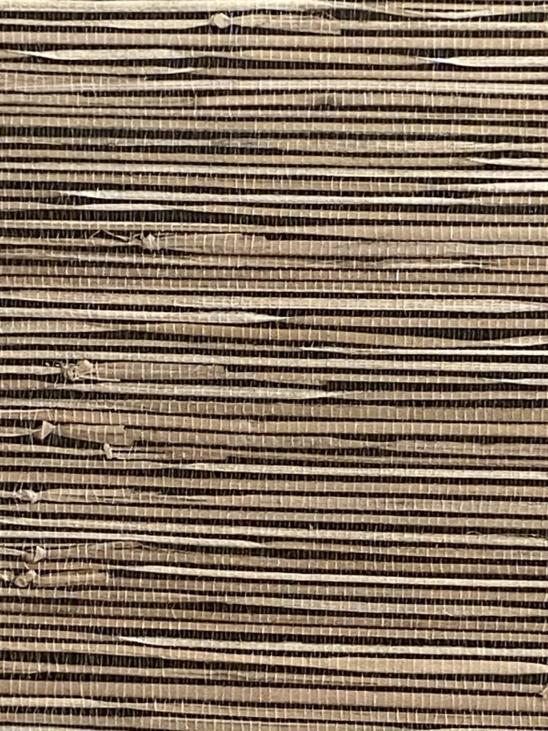zbliżenie na tapetę tkaną z seegrasu widoczne zgrubienia, nierówności i nitki montażowe, kolory brąz i beż