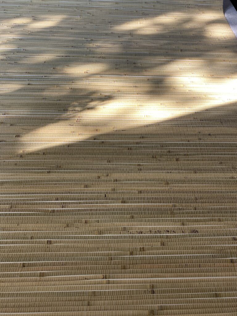 zbliżenie na naturalną tapetę z bambusa w kolorze seledynowym z widoczną grą światłem