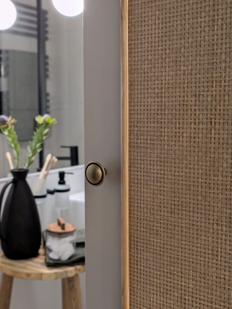 zbliżenie na drzwi szafy oklejonej tapetą z plecionki papierowej w kolorze beżowym