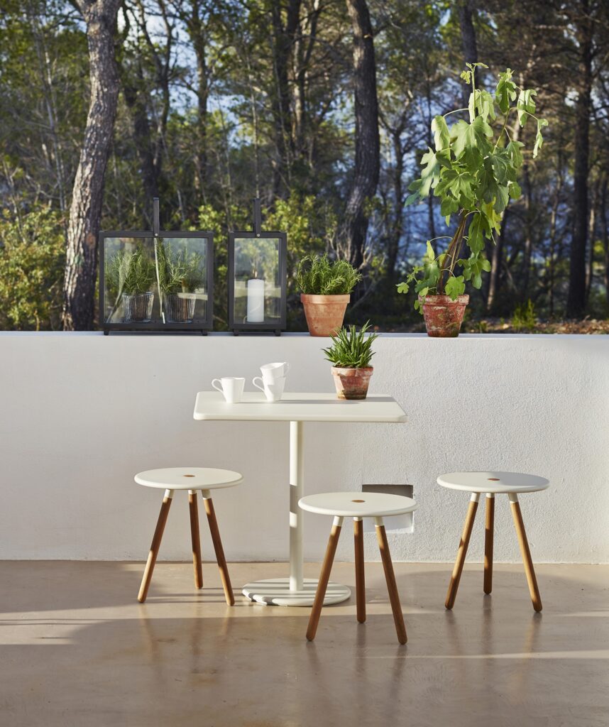 stołki z białego aluminium i drewna teak przy okrągłym stole w białym kolorze