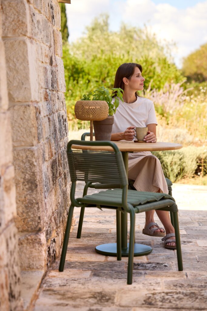 zielone krzesło strunowe przy okrągłym stoliku, młoda kobieta siedzi na drugim krześle