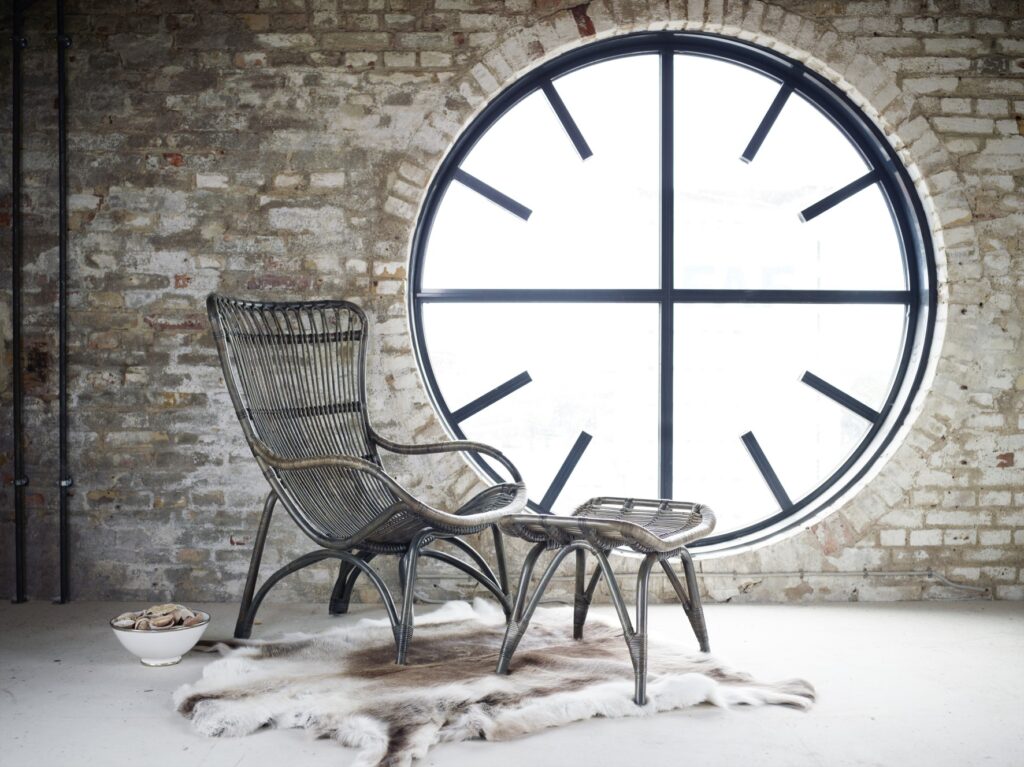 na poddaszu stoi fotel rattanowy z podnóżkiem