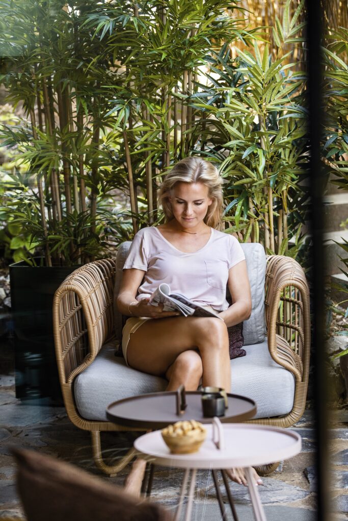 młoda kobieta czyta gazetę siedząc na wygodnym fotelu outdoor Nest