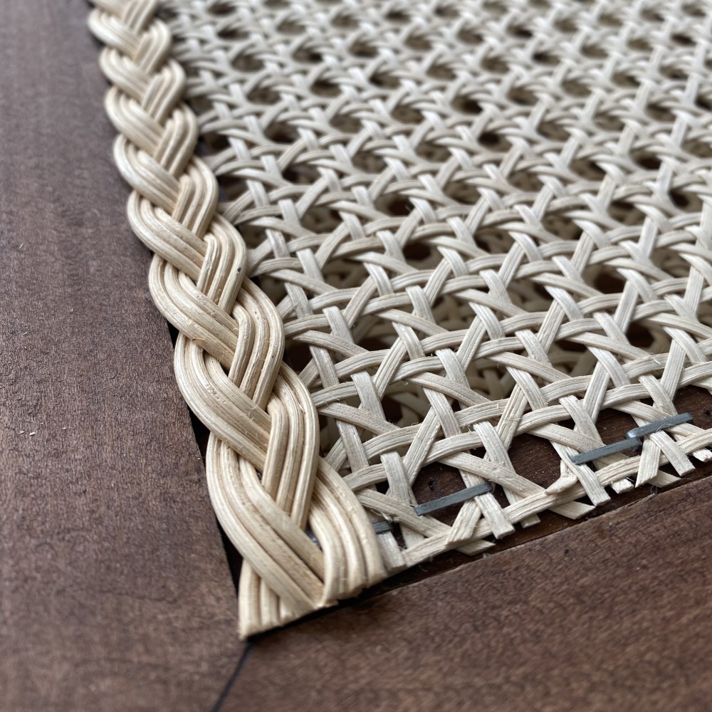 Zbliżenie na fragment fronty meblowego z plecionką rattanową i łączenie zasłonięte warkoczem rattanowym