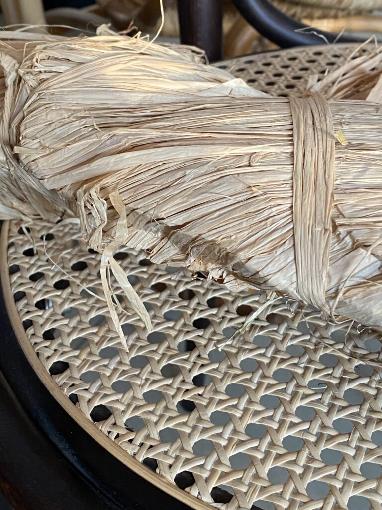 zbliżenie na warkocz rafii leżący na siedzisku z plecionki rattanowej