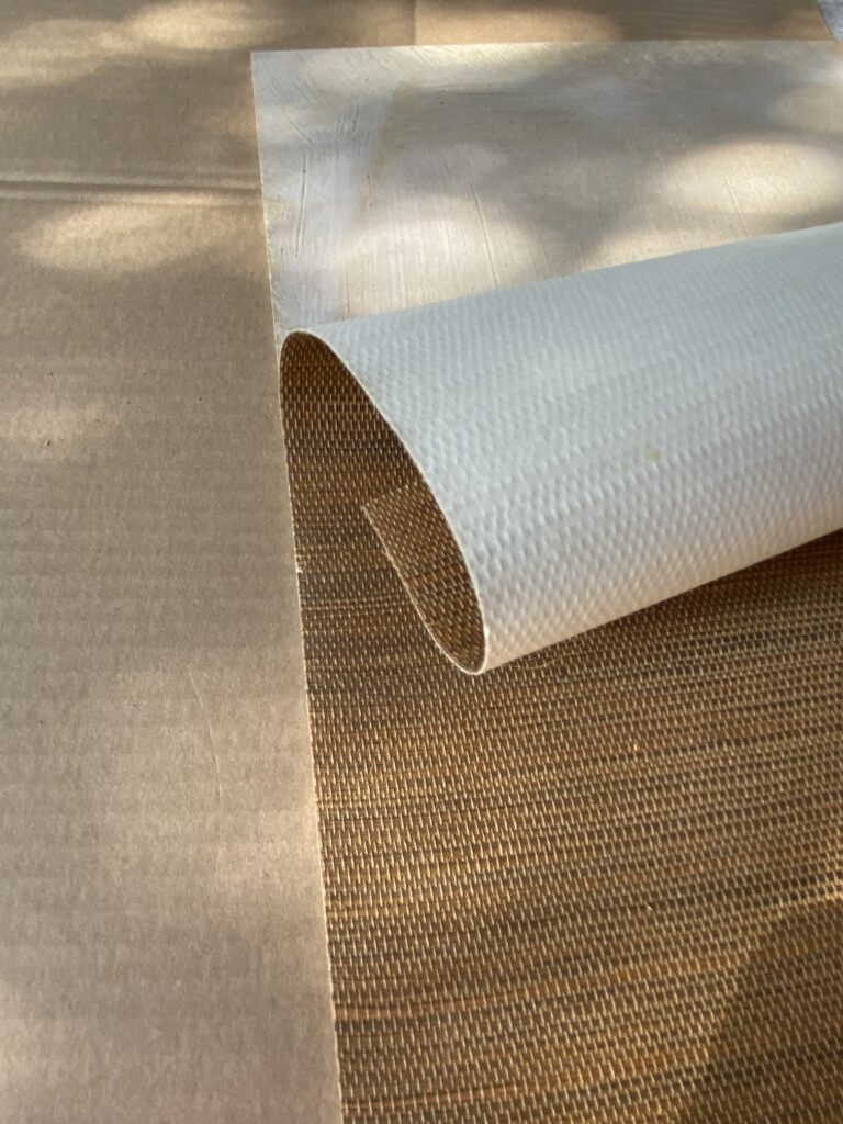 Klejenie tapety z sizalu na płytę meblową. Widoczny fragment płyty pokryty klejem.