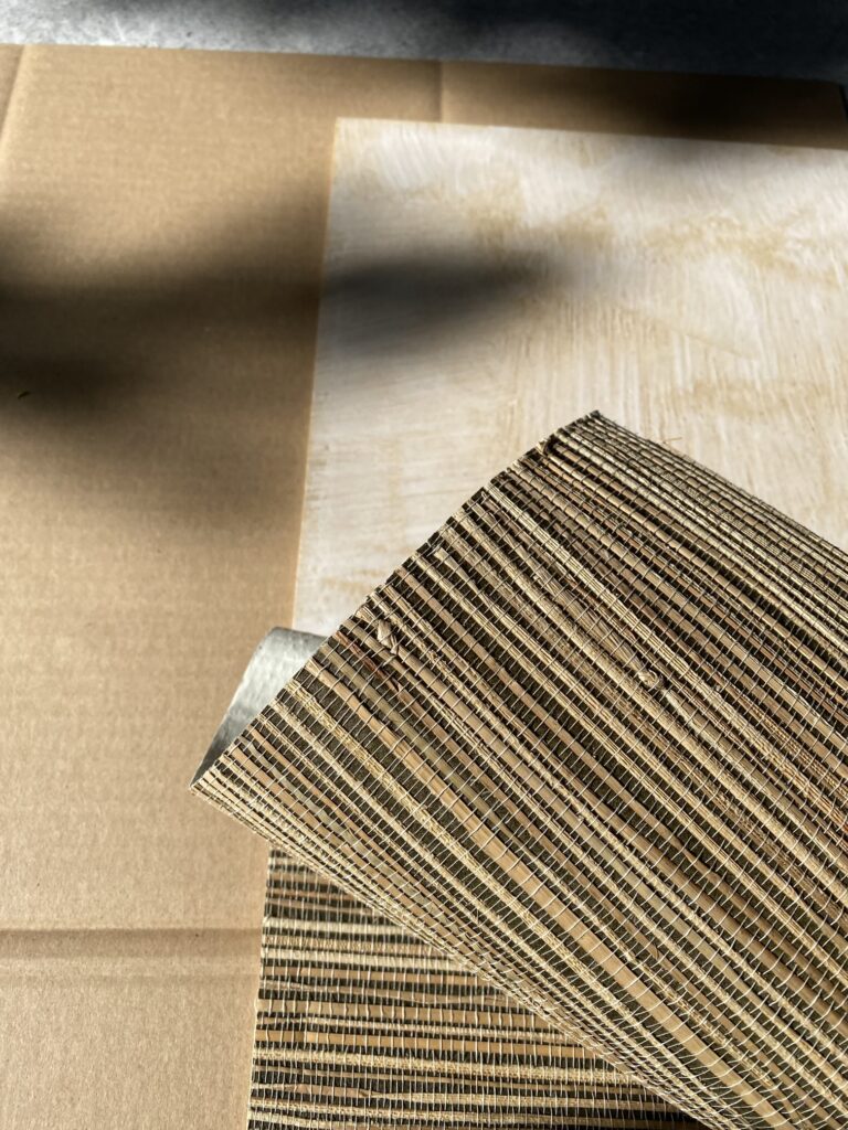 Tapeta z trawy morskiej naklejana na płytę meblową. Widoczny fragment płyty pokryty klejem