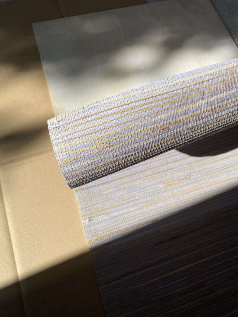 Tapeta z trawy morskiej naklejana na płytę meblową. Widoczny fragment płyty pokryty klejem