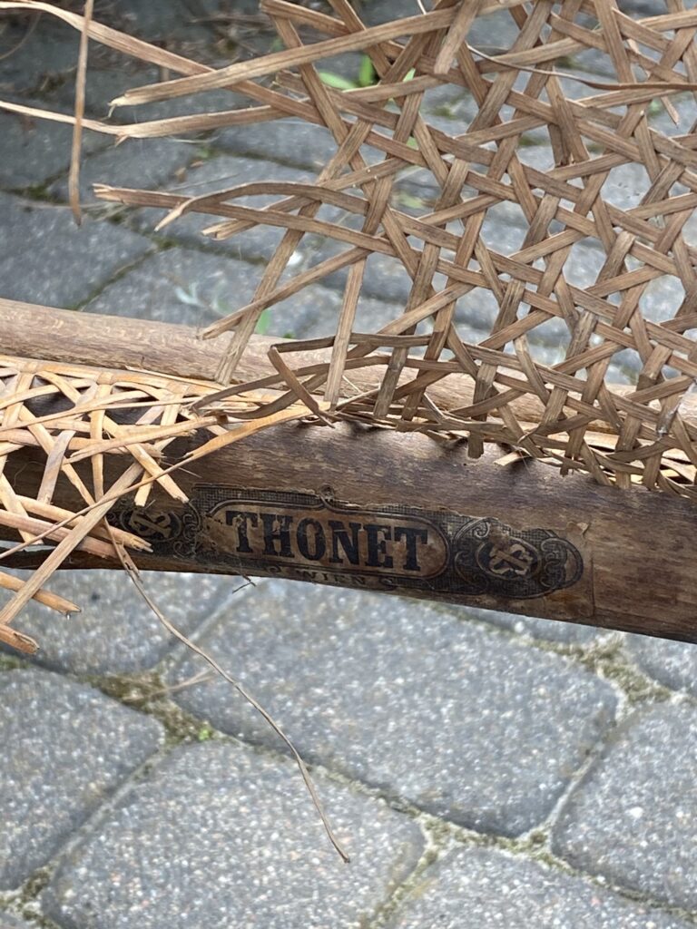 Uszkodzony rattan w siedzisku fotela Thonet. Widoczna sygnatura.