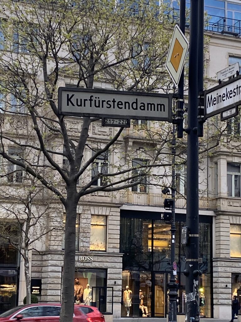 Skrzyżowanie Kurfürstendamm i Meinekestraße w Berlinie z zabytkowymi kamienicami i tablicą uliczną Kurfürstendamm